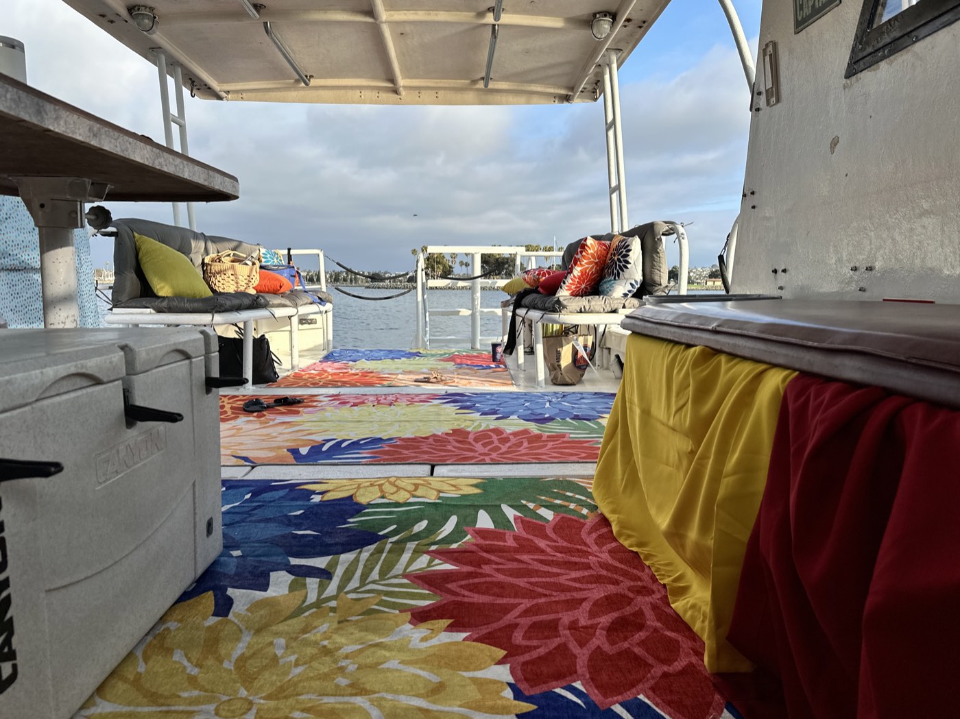 The back deck of the Marissa with its cushions and bright rug, Mission Bay beyond